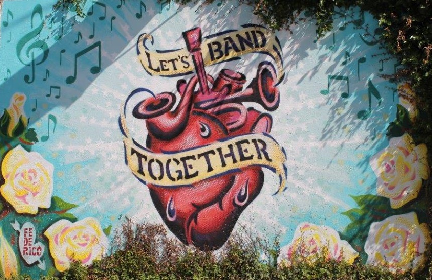 Site image highlighting local art: Graffiti image of a heart, musical instruments, music notes, flowers and text reading Lets band together.